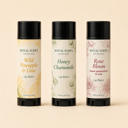 Three Ritual Lip Balm tubes standing side by side — Wild Pineapple & Lime, Honey Chamomile, and Rose Bloom — in cream botanical labels with black caps