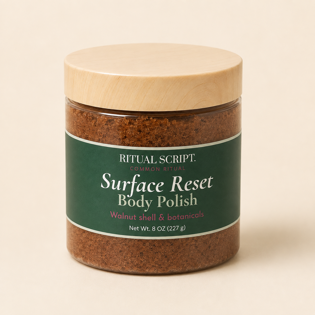 Surface Reset Body Polish in a clear 8 oz jar with a wooden lid and forest green label, showing the brown walnut shell scrub inside