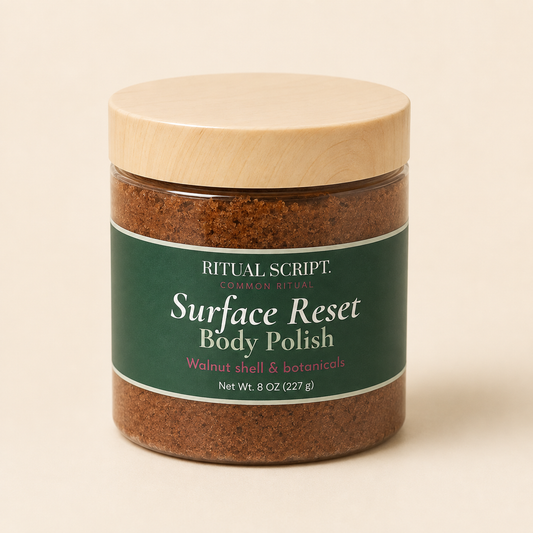 Surface Reset Body Polish in a clear 8 oz jar with a wooden lid and forest green label, showing the brown walnut shell scrub inside